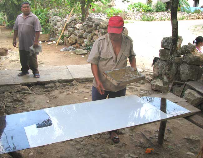 With the mold filled with mixed fibers, Don Pascual approaches his paper-making table.